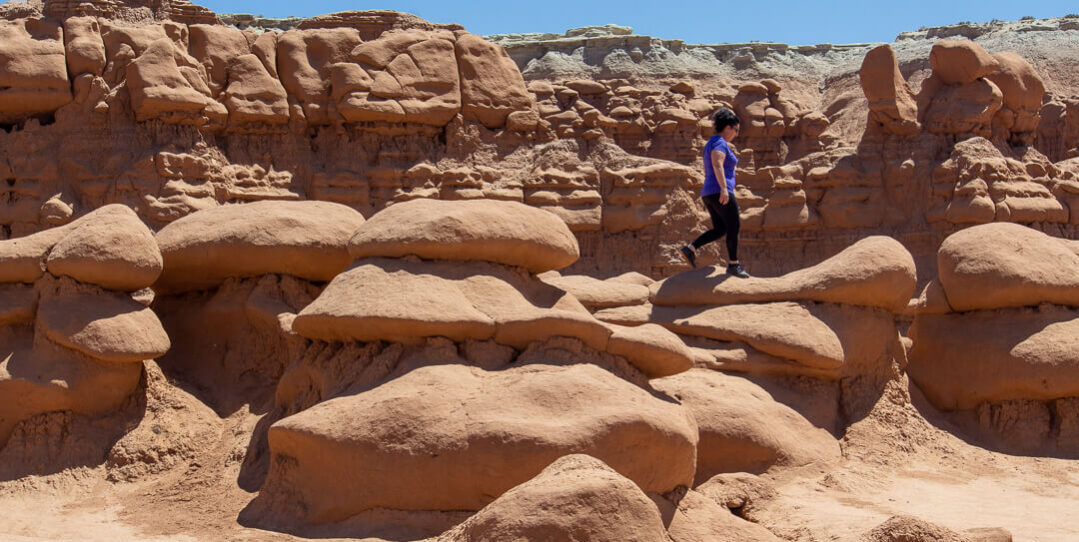 woman walking across hoodoos